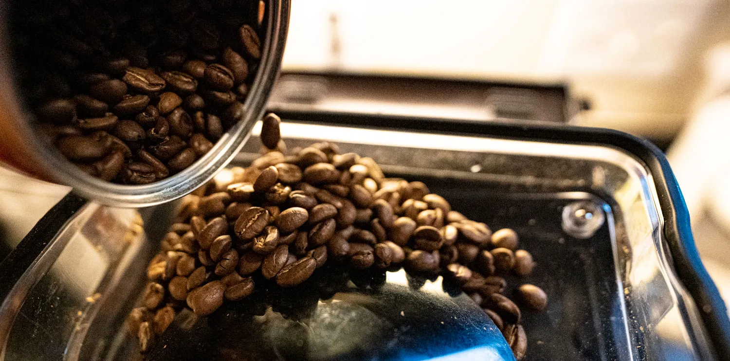 Pouring Illy Colombian beans into coffee grinder's hopper